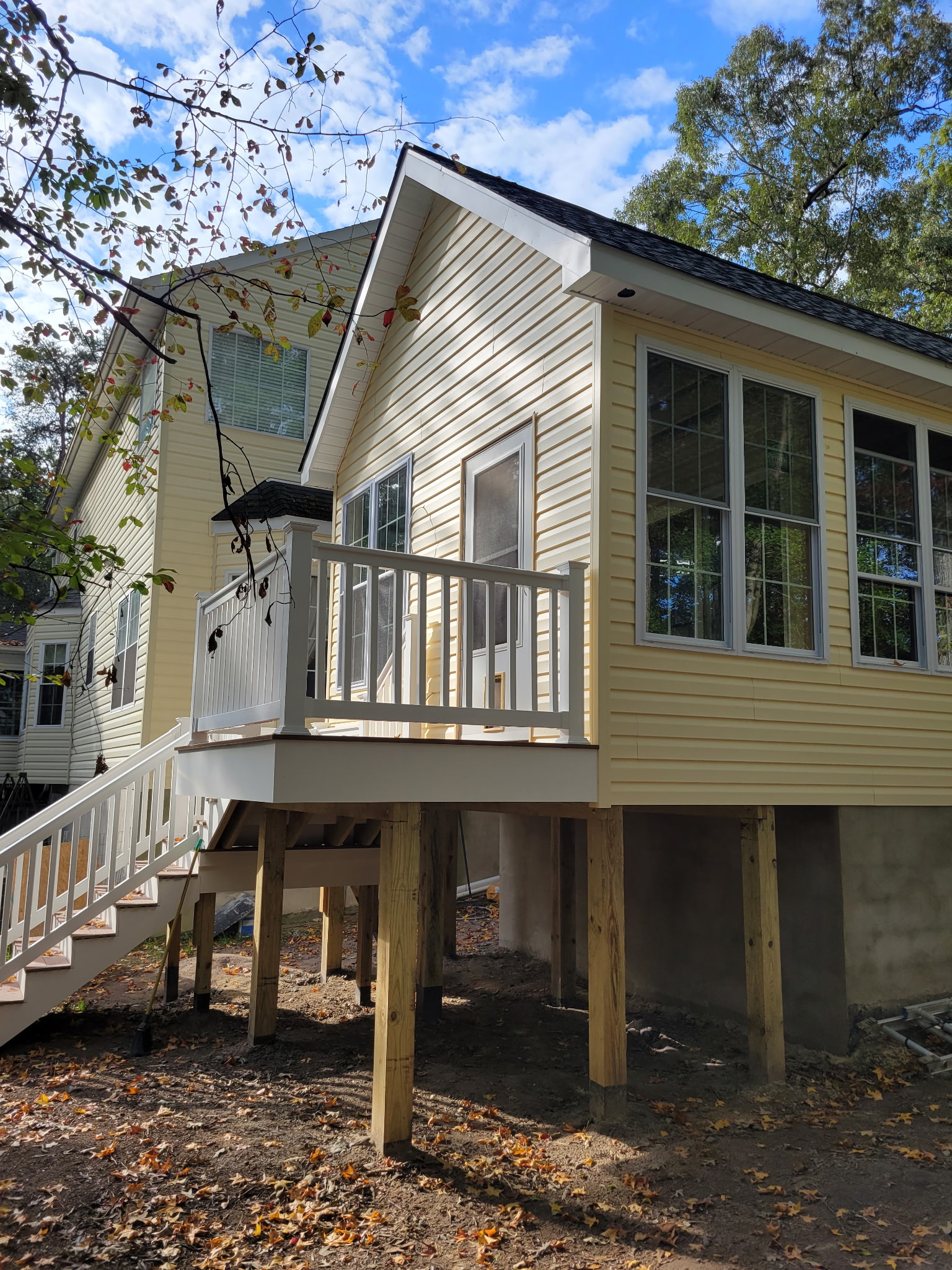 Exterior home addition with a raised deck, white railing, and stairs