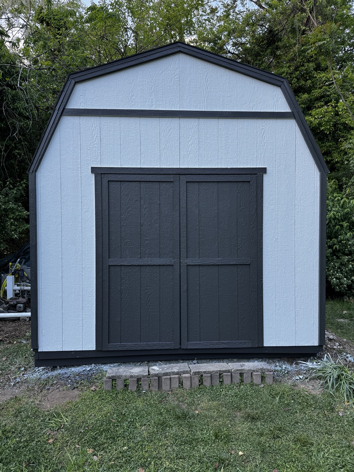 Backyard shed after white and black exterior refinishing