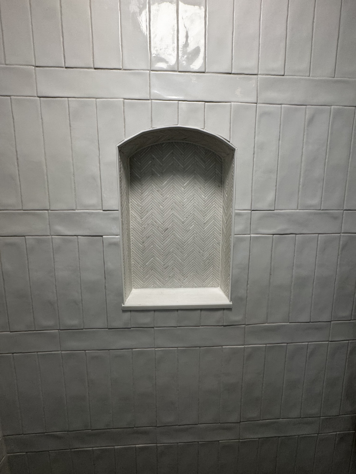 Detailed arched shower niche with herringbone tile