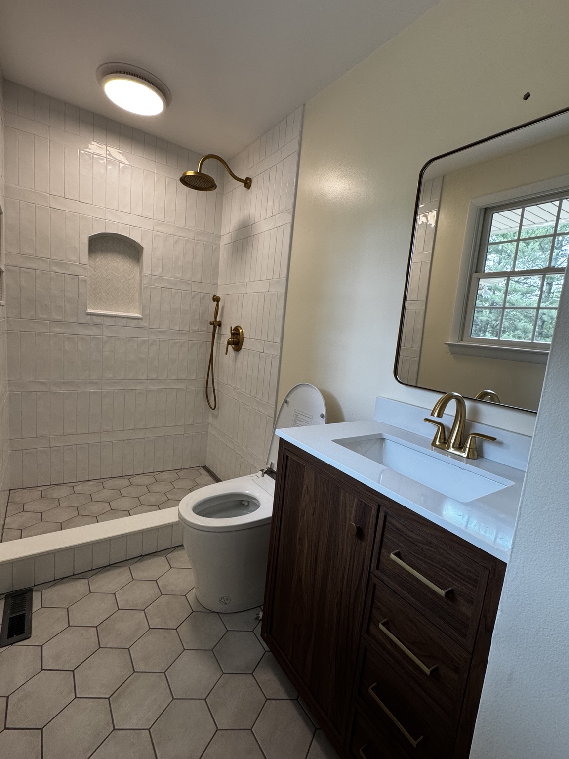 Finished custom tile shower with brass fixtures and hexagon tile floor
